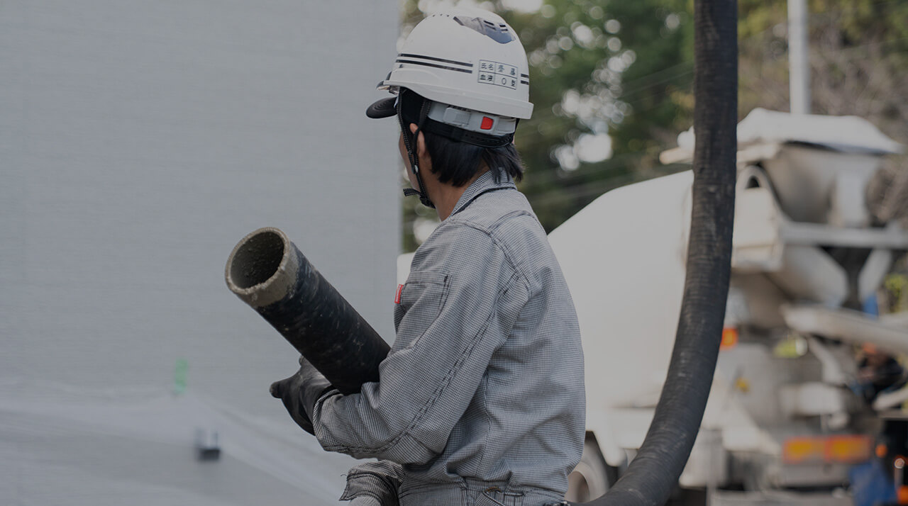 コンクリートミキサー車の太いホースを支える職人